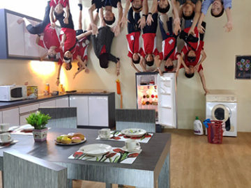 Camp kids at trick art museum appearing to be sitting on ceiling