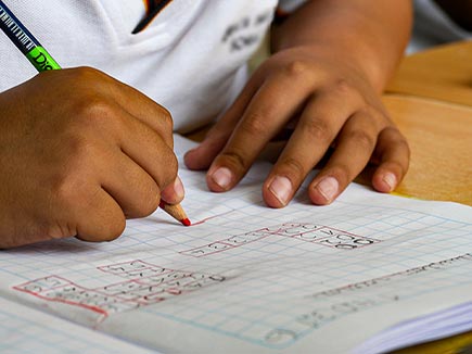 boy writing in workbook with a pencil